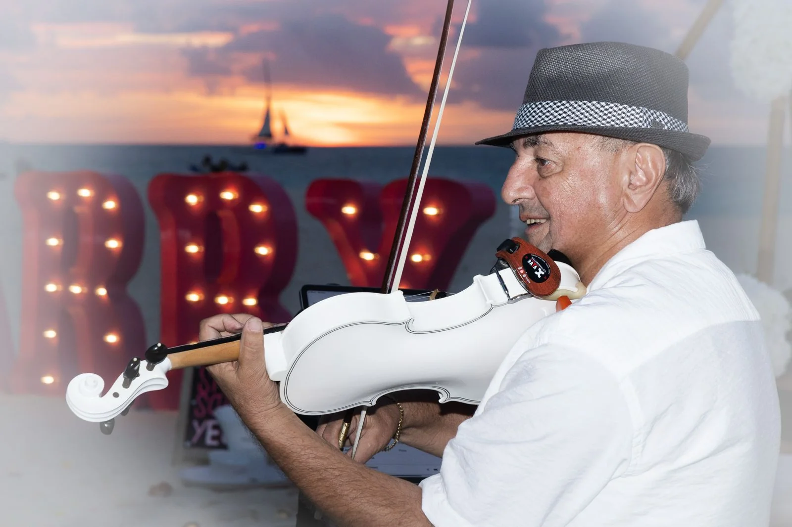 Nicola playing a white violin at a sunset proposal